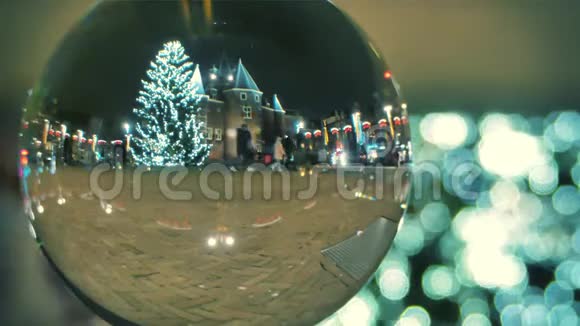 不知名的游客走在为圣诞节和新年装饰的广场上透过玻璃球观看视频的预览图