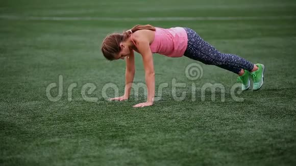 一个穿着紧身衣和背心的漂亮肌肉女孩在体育场做热身交叉健身健身健康的生活方式视频的预览图
