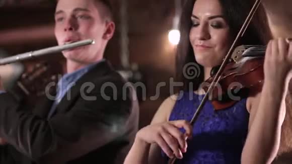 两个人演奏音乐一个穿着蓝色连衣裙的漂亮黑发女子正在拉小提琴而那个穿夹克衫的家伙视频的预览图