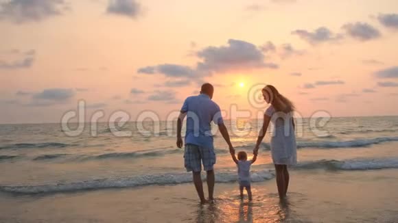 幸福的一家人在日落时沿着海边散步视频的预览图