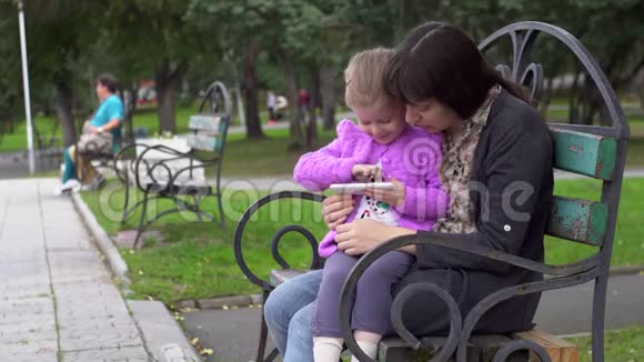家庭母女在公园阴天玩智能手机视频的预览图