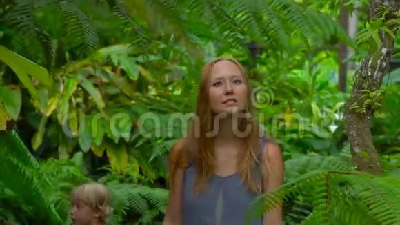 年轻女子和她的儿子参观了一个热带植物园蕨类植物视频的预览图