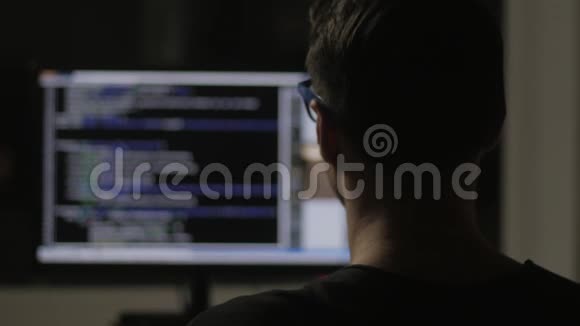 在黑暗的房间里从后面编程并在电脑显示器上编程代码视频的预览图