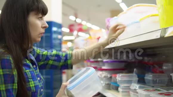 一个年轻的女人选择并在超市买一个塑料容器作为食物视频的预览图