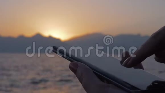 在海上和日落时使用手机的女人视频的预览图