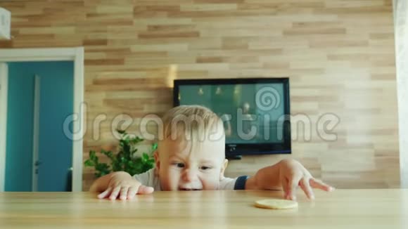 有趣的孩子爬到桌子上吃饼干带孩子概念的好奇视频视频的预览图