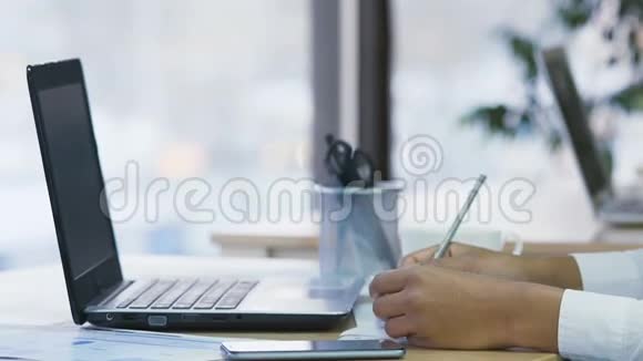 女秘书用钢笔写笔记用手提电脑打字视频的预览图