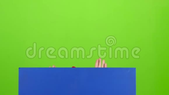 快乐的小男孩从海报后面偷看站在绿色屏幕上举着广告牌慢动作视频的预览图