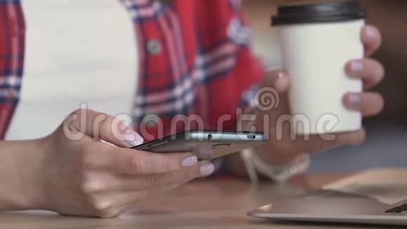 在咖啡馆的咖啡休息时间年轻女子的手在智能手机上滑动图片视频的预览图