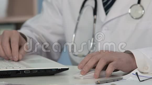 男性医生使用电脑鼠标和在笔记本电脑上输入信息的手视频的预览图