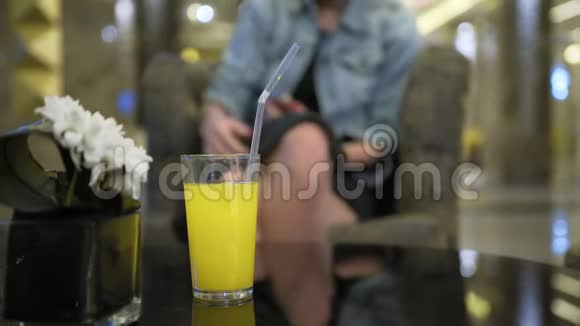 年轻的白人女性穿着牛仔裤夹克从杯子里喝果汁使用智能手机在社交网站上留言视频的预览图