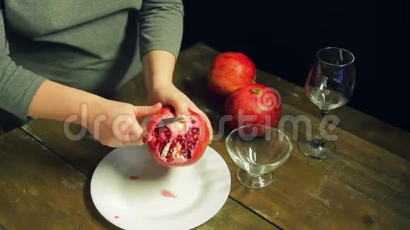 女人用刀子在木桌上的白色盘子上清洗石榴果实视频的预览图