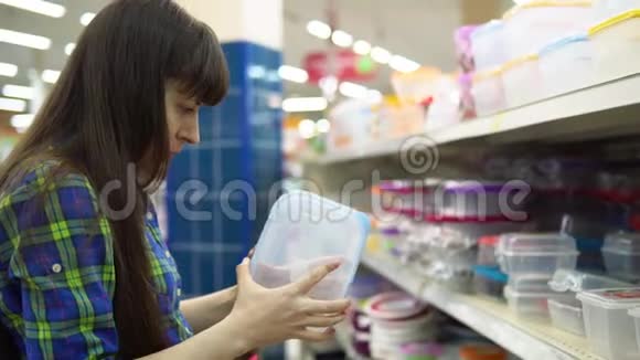 一个年轻的女人选择并在超市买一个塑料容器作为食物视频的预览图