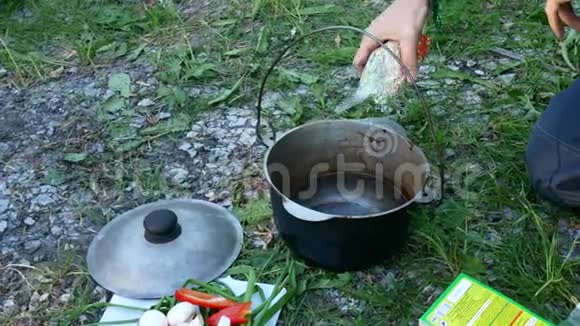在旅游营地做饭一个人把一包豆子倒进锅里视频的预览图