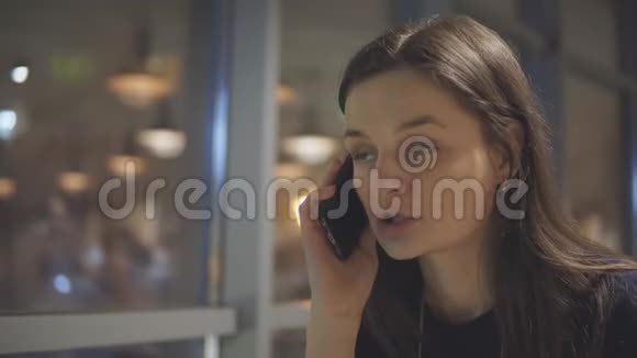 一个漂亮的女孩在咖啡馆里用手机说话视频的预览图