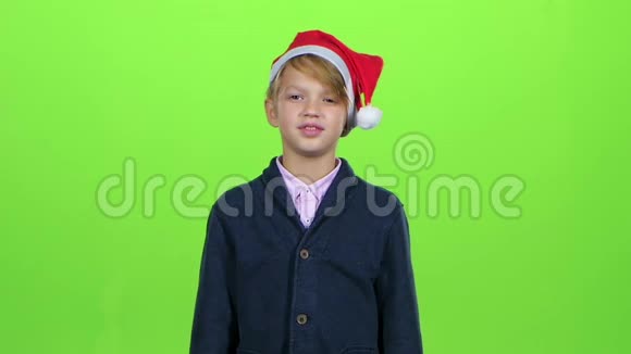 戴着桑塔劳斯帽的小男孩举起手在绿色屏幕上显示卡片慢动作视频的预览图