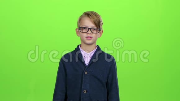 带着眼镜的小男孩看着信用卡在绿色的屏幕上表现出厌恶慢动作视频的预览图