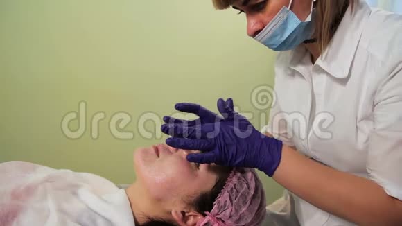 美容师在女人的脸上涂了一层舒缓霜中胚层治疗后皮肤发红发炎特写视频的预览图