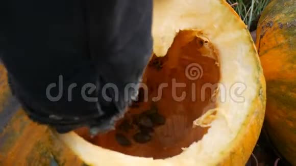 男人打扫南瓜的内部手从里面取出南瓜籽准备万圣节视频的预览图