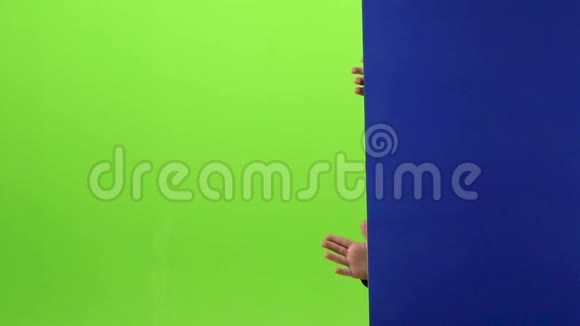 戴着圣诞帽的小男孩从墙后出来在绿色的屏幕上显示舌头慢动作视频的预览图