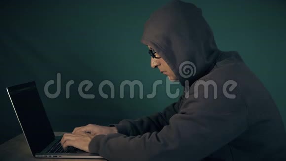 他是个流氓白人坐在桌子旁在笔记本电脑上打字戴眼镜的家伙视频的预览图