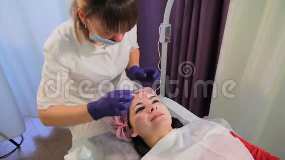 美容师从女人的脸上摘下面具治疗后皮肤发红刺激Bb发光视频的预览图