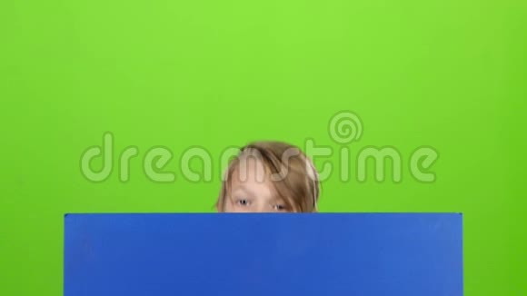 十几岁的孩子拿着两个芯片从董事会后面出来在绿色的屏幕上显示舌头慢动作视频的预览图