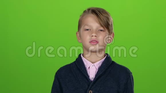 穿着开襟羊毛衫的少年在寻找芯片在绿色屏幕上消极地挥动着他的头慢动作视频的预览图