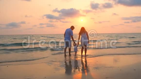 幸福的一家人在日落时沿着海边散步视频的预览图