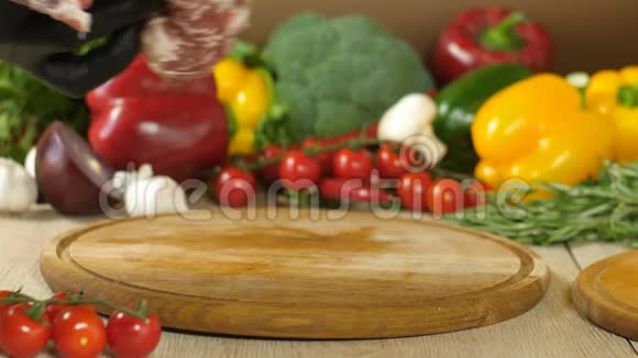 厨师把一块生的多汁的肉扔在一块圆木板上背景是蔬菜花椰菜红椒视频的预览图