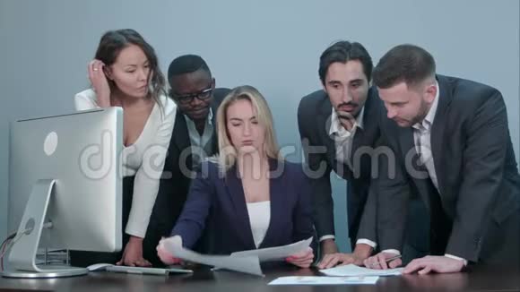 一群商务人士在会议期间忙于讨论财务问题站在女老板桌旁视频的预览图