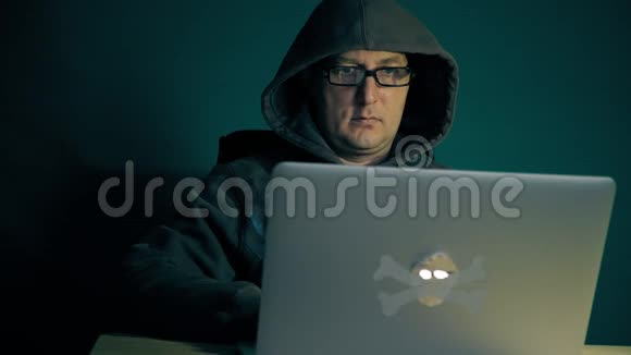 成年白种人黑客坐在桌旁手提电脑时尚眼镜编码黑客利用网络程序视频的预览图