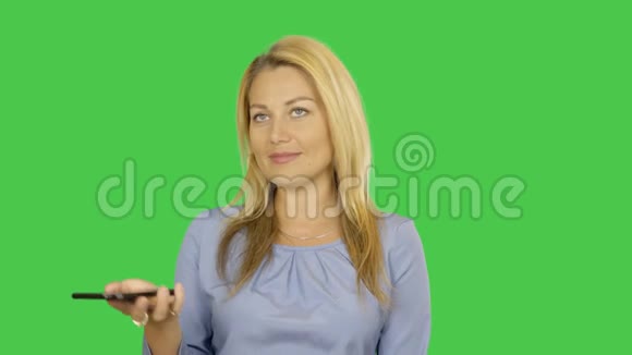 可爱的金发女人在电话里讲话的特写镜头她微笑着站在一边阿尔法通道键控绿色屏幕视频的预览图