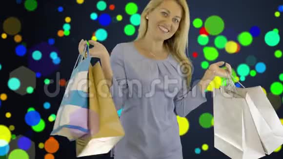 白人年轻女子站着手里拿着购物袋旋转快乐可爱的女人色彩斑斓的背景视频的预览图