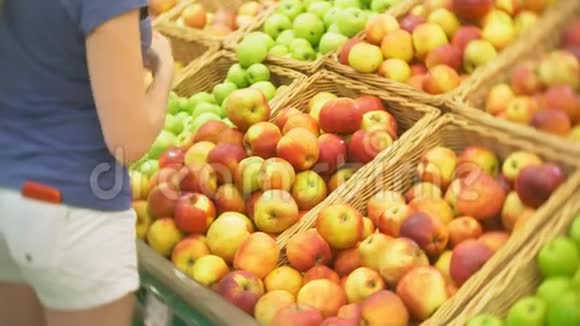 年轻女子在水果蔬菜超市市场选择苹果4k视频的预览图