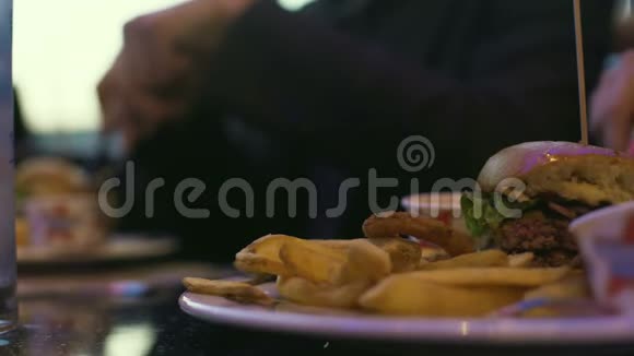 人们坐在咖啡馆里交流吃热卡汉堡和炸薯条视频的预览图