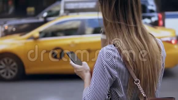 年轻漂亮的女商人站在路边喝着咖啡用着智能手机女的在等出租车视频的预览图