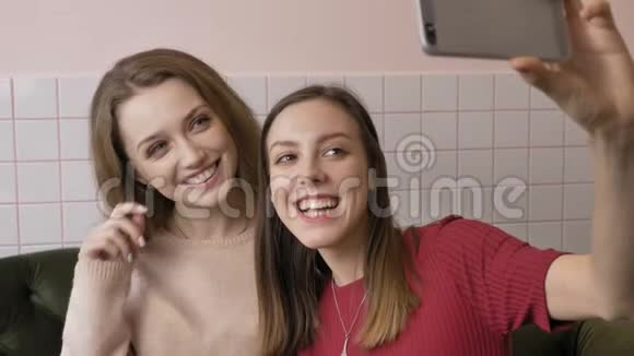 两个年轻的白种人漂亮的女孩坐在咖啡馆里自拍笑着微笑着女朋友朋友视频的预览图