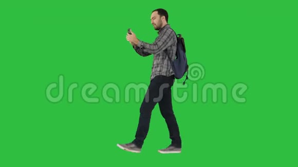 年轻有吸引力的学生背包游客自拍照片与手机上的绿色屏幕铬键视频的预览图