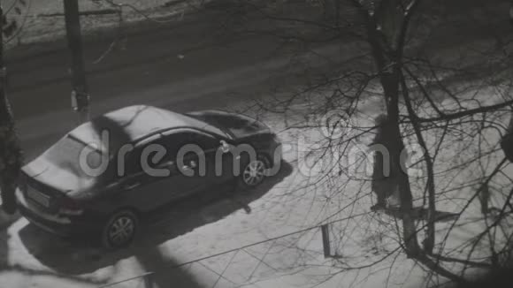 在冬天的雪夜路灯柱下人们在停放的汽车旁行走视频的预览图