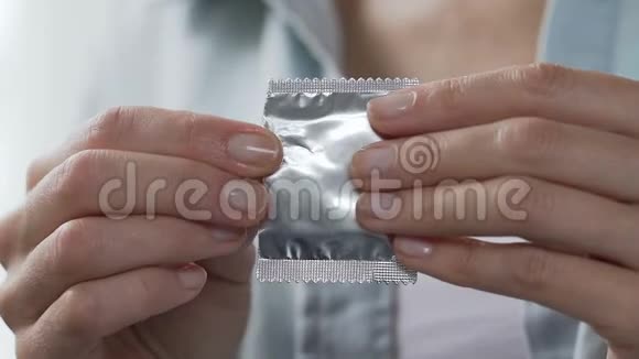 女孩手指从包裹中取出避孕套预防艾滋病毒艾滋病避孕视频的预览图