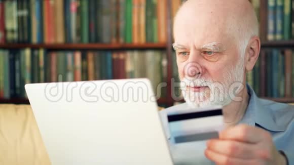 英俊的胡子老人坐在家里在网上用信用卡购物视频的预览图