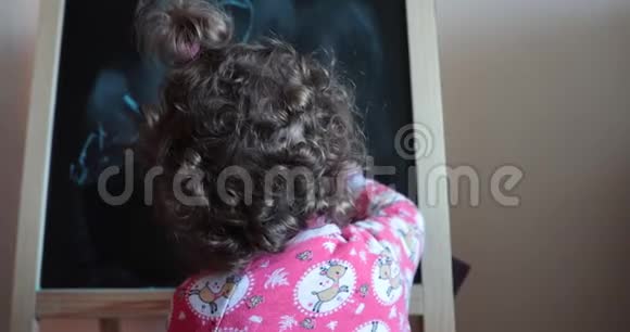 幼儿用粉笔在黑板上画画背面视图视频的预览图