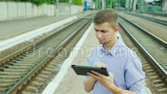 一个年轻的商人在火车站用平板电脑在等火车视频的预览图
