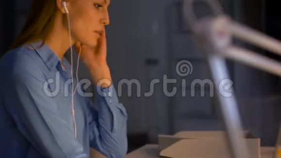 女商人在夜间办公室听音乐视频的预览图