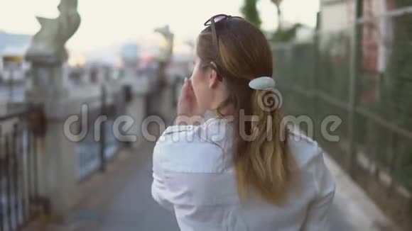年轻漂亮的女孩走在美丽的城市景观的背景上视频的预览图