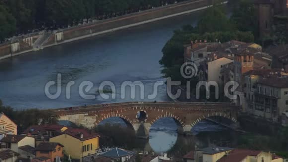 历史拱桥连接两个河岸在黄昏与人步行视频的预览图