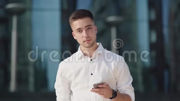 穿着白色衬衫的现代年轻人站在一座玻璃建筑旁边视频的预览图