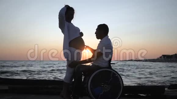 残疾人晚上听妻子腹部残疾配偶坐轮椅日落时怀孕女性视频的预览图
