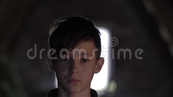 一个严肃悲伤的男孩在黑暗的房间里看着摄像机视频的预览图